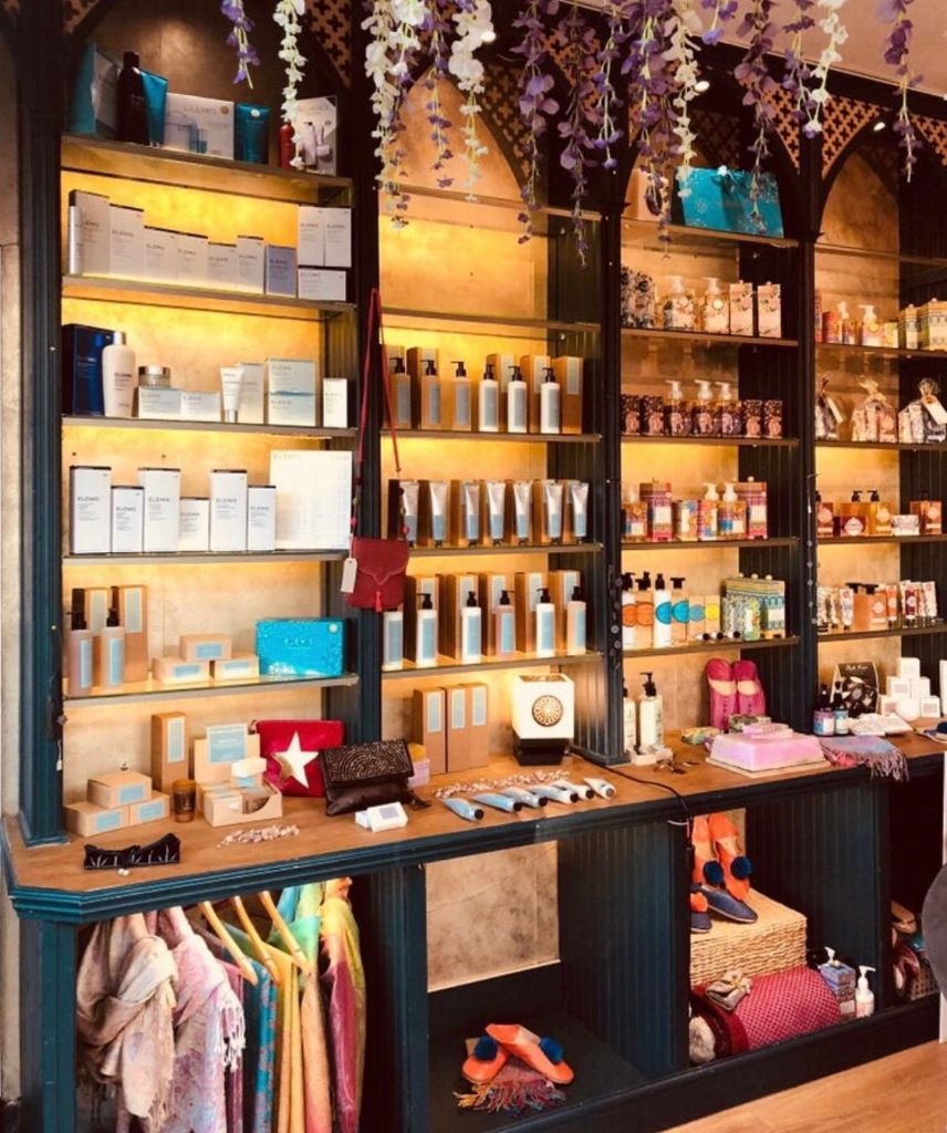 Hudson & Wood shop shelves filled with skincare, gifts and colourful accessories beneath hanging flowers