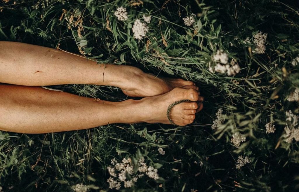 Bare feet resting in long grass and wildflowers