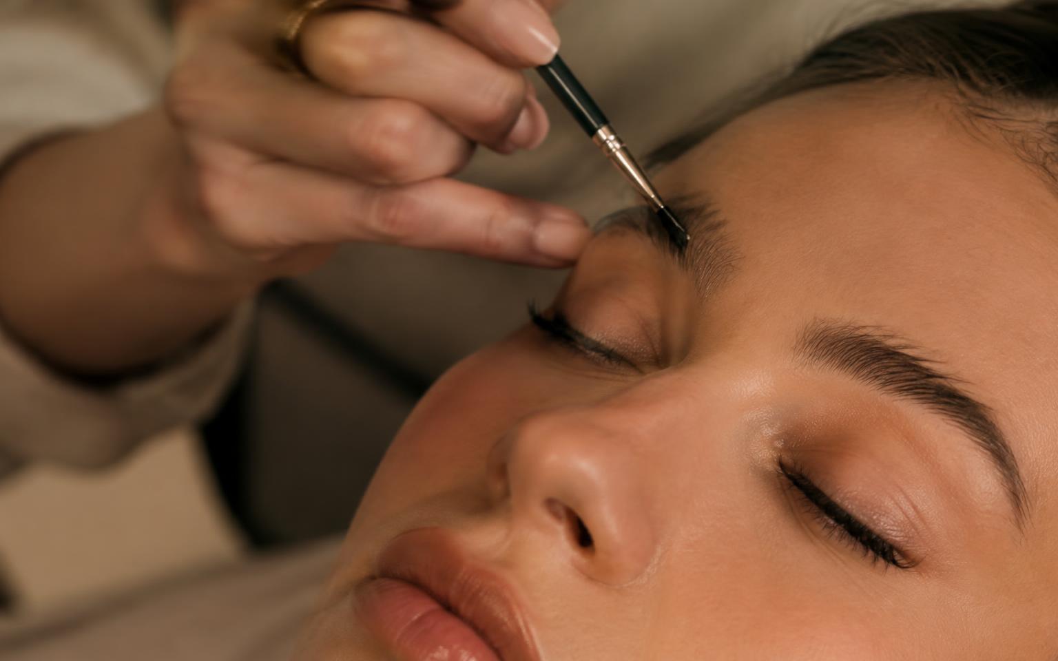 Brow tint being brushed on with a fine brush