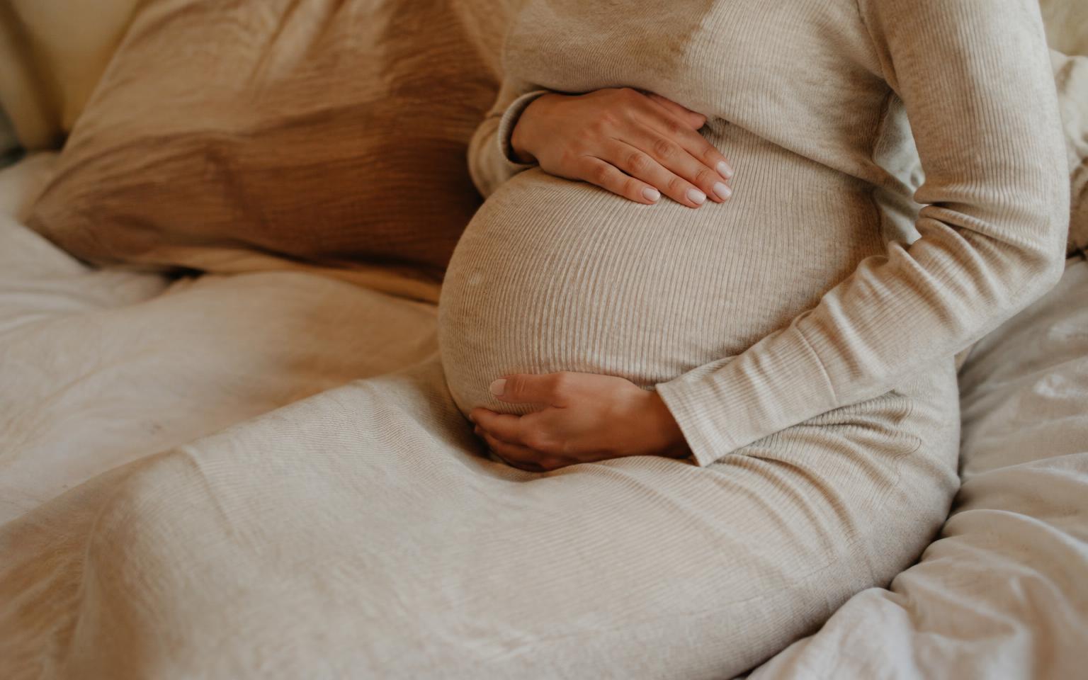 Expectant mother cradling her bump in soft knitwear